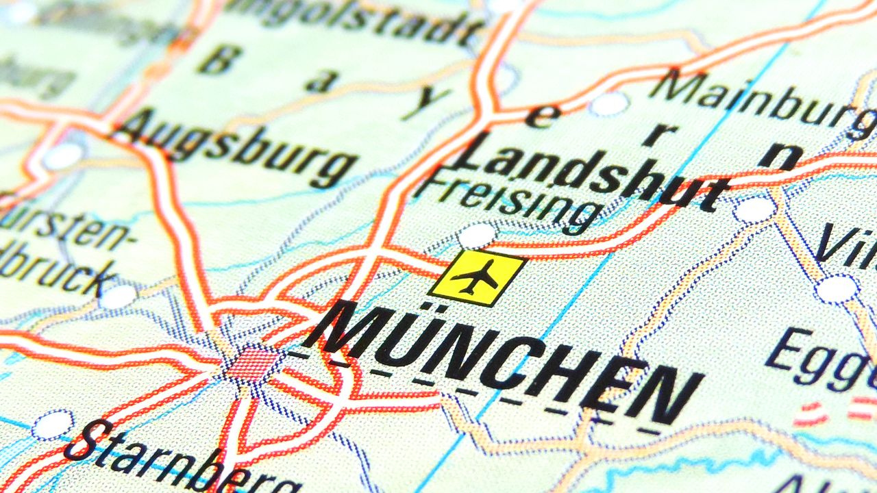 Detailausschnitt einer Landkarte mit dem Fokus auf München, gekennzeichnet durch ein gelbes Feld mit einem Flugzeugsymbol, umgeben von anderen Städten und Netzwerken aus Straßen und Flüssen.