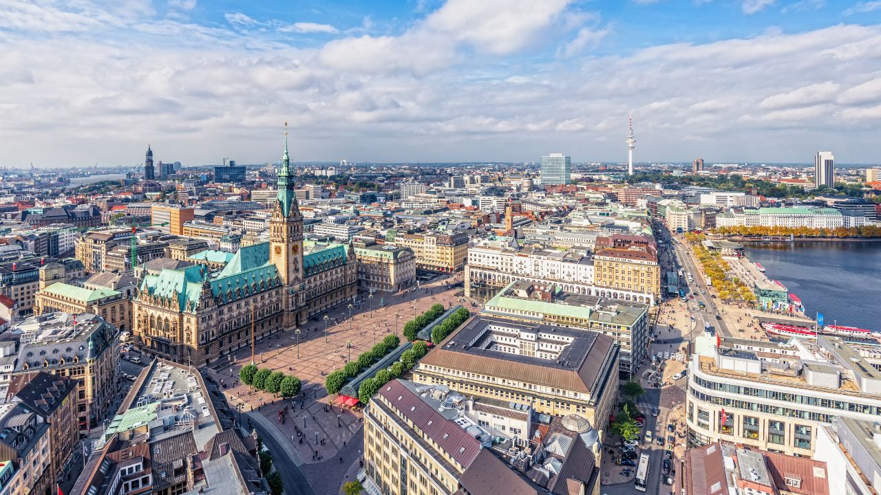 Panoramablick über Hamburg mit dem markanten Rathaus, der Binnenalster und weitläufigen städtischen Strukturen bei klarem Wetter, symbolisch für den beständigen Wohnungsmarkt der Stadt.